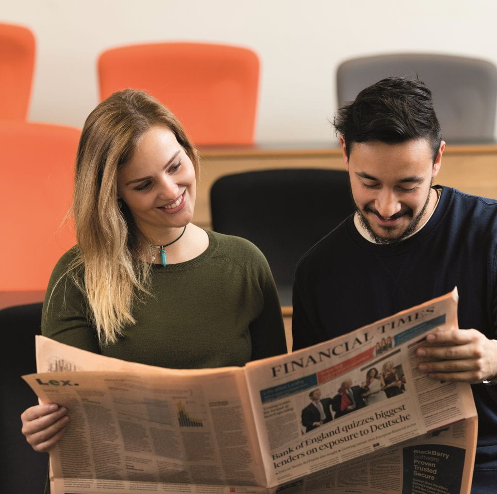 Image of two University of Lincoln Journalism students reading a newspaper together.